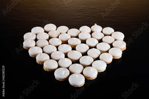 Small cookies laid in the shape of heart on black background. Selective focus. Shallow depth of field photo