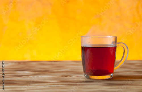 Cup of tea on light wooden table on blur jute background. Selective focus. Shallow depth of field