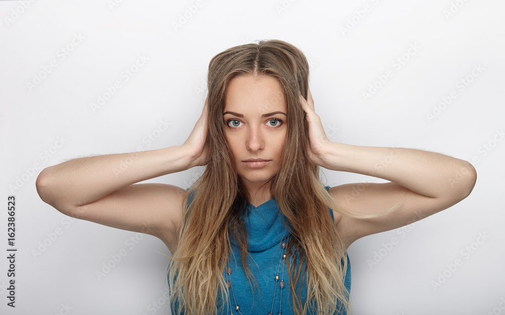 Headshot of young adorable blonde woman with cute smile on white background covers her ears with palms Headshot of young adorable blonde woman with cute smile on white background covers her ears with palms