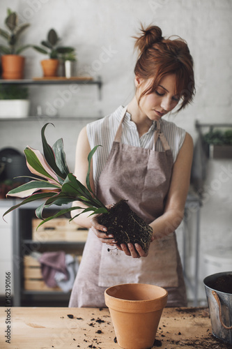 Pretty Caucasian woman florist planting at her workshop.