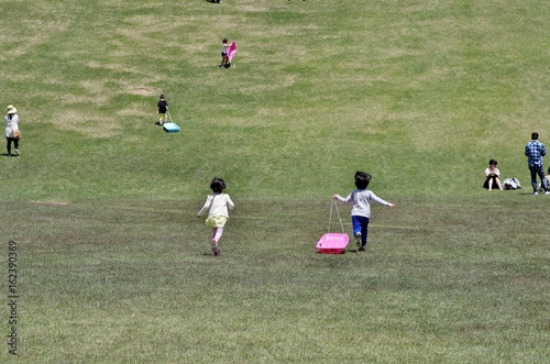 夏の草原でそり遊びをする子供たち © goro20