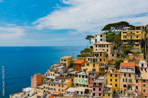 view of famous travel landmark destination Riomaggiore colorful houses, small mediterranean old sea town,Cinque terre National Park, Liguria, Italy. Summer sunny morning with clouds