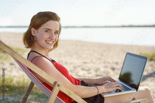 Smiling happy young woman working on a laptop