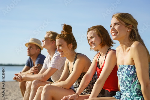 Row of happy young students relaxing in summer