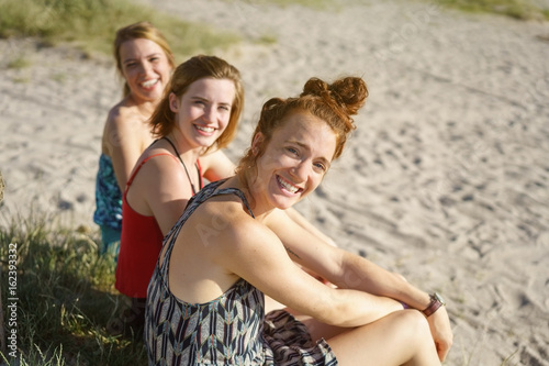 Three happy girlfriends relaxing on a sandy beach