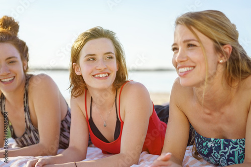 Three pretty young woman lying on a beach © contrastwerkstatt