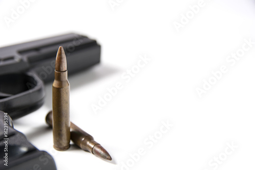 Hand gun sitting with m-16 bullets isolated on white background.