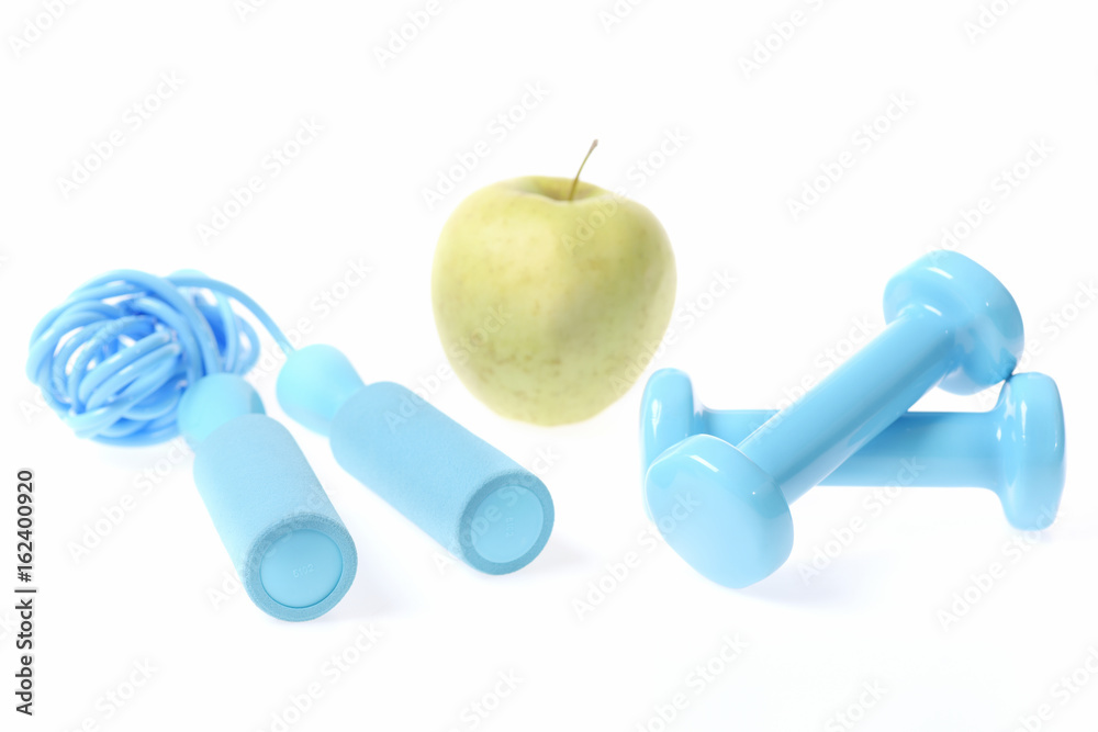 Healthy lifestyle composition: fresh green apple with cyan blue dumbbells Healthy lifestyle composition: fresh green apple with cyan blue dumbbells