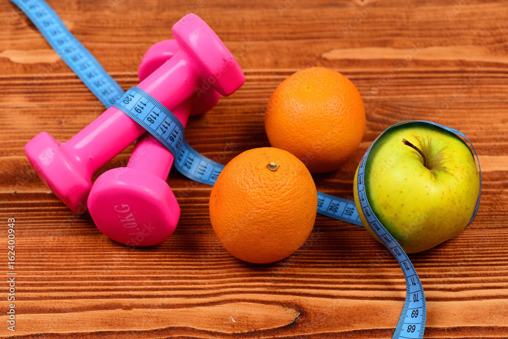 sport object concept, dumbbells with measuring tape, orange and apple sport object concept, dumbbells with measuring tape, orange and apple