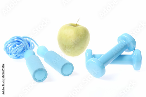 Healthy lifestyle composition: fresh green apple with cyan blue dumbbells