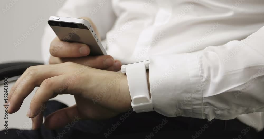 Close-up business man in a white shirt making gestures on a wearable smartwatch computer device. Close-up business man in a white shirt making gestures on a wearable smartwatch computer device.