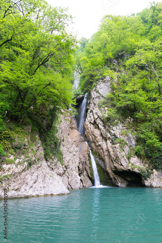 Waterfall in green subtropical mountains  flowing in the lake