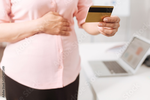 Pleasant pregnant woman holding a credit card