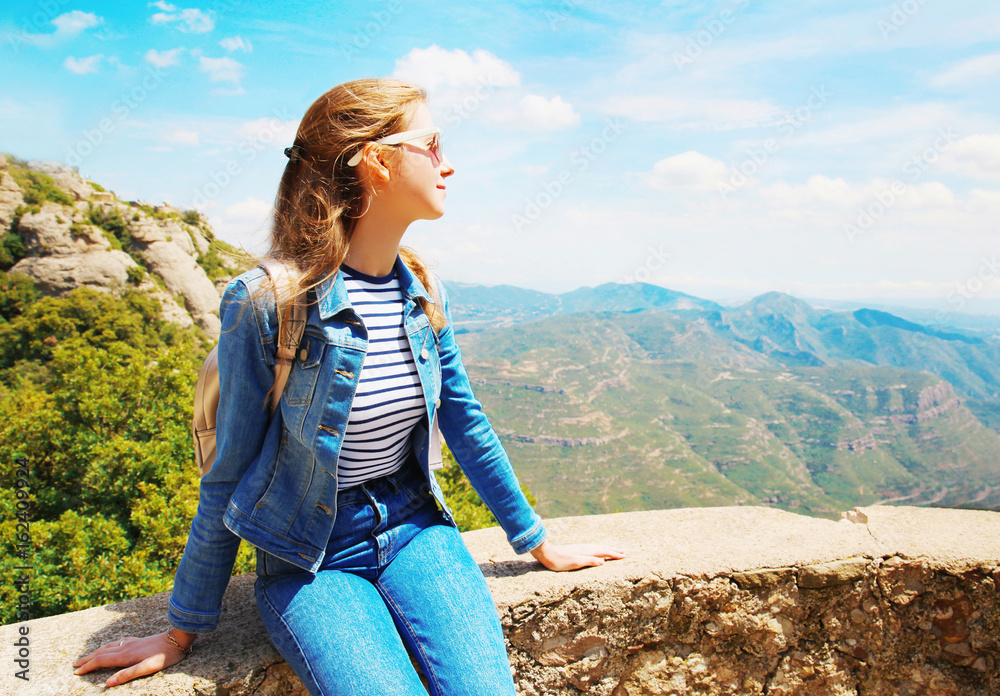 Travel young woman sitting on the rocks, mountains Spain background and blue sky