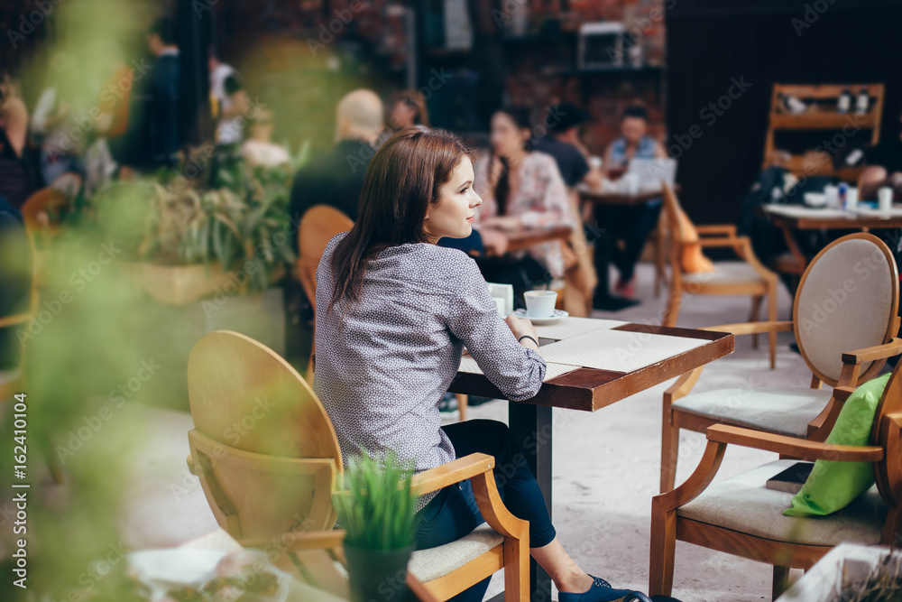 Beautiful girl in a cafe. Shot through the foreground Beautiful girl in a cafe. Shot through the foreground