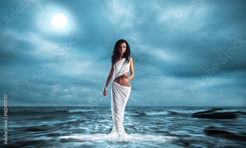 Fashion shoot of Aphrodite styled young woman over ocean background. photo