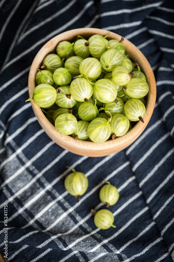 Fresh gooseberry in a wooden bowl.