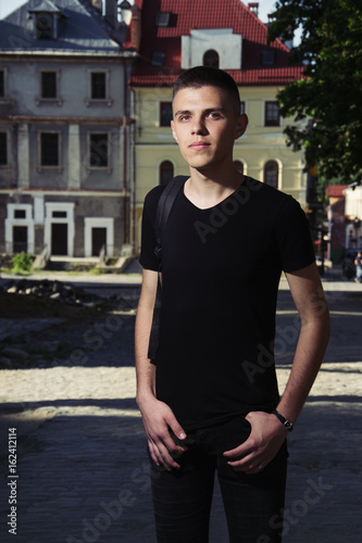 happiness and people concept - smiling man in black t-shirt over house background, toned photo © Олександр Болюх