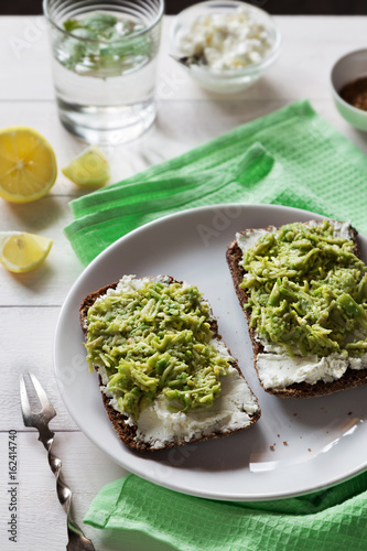 Avocado sandwich with cottage cheese on white plate