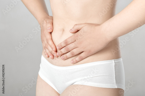 Woman with abdominal pain on gray background © producer