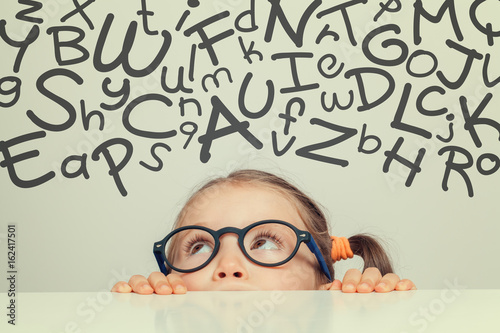 beautiful cute little girl with handwritten letters of alphabet above her head