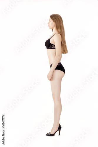 Profile of young  slim woman in black lingerie isolated on white background