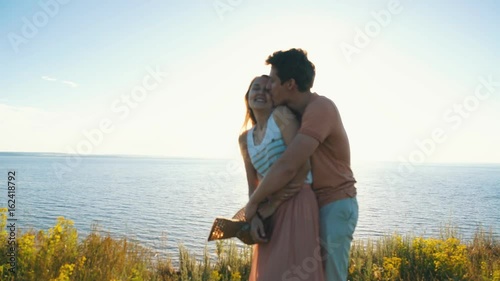 happy couple dancing at the edge of the cliff on the background of the river photo