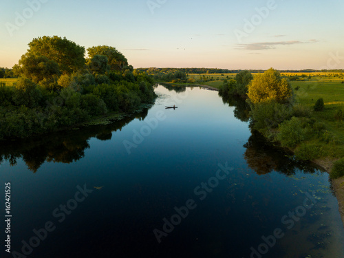 Silhouette of a fisherman in a boat on a river at sunset