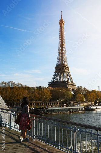 Young girl standing on a bridge, admiring the Eiffel tower in the last rays of the sun. Paris. France. © Artem Kudryavtsev