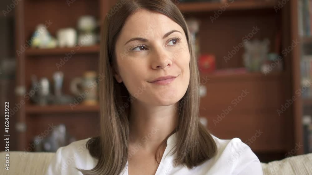 Slow Motion Portrait of beautiful attractive young woman in white blouse sitting on sofa in living room thinking Slow Motion Portrait of beautiful attractive young woman in white blouse sitting on sofa in living room thinking