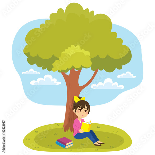 Young little girl reading a book under tree
