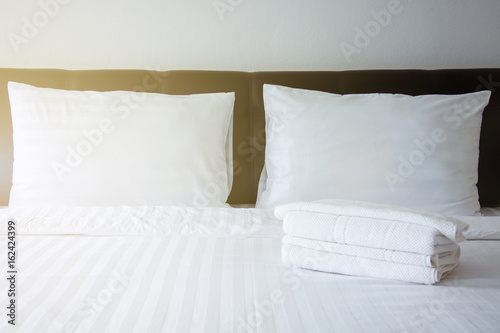 Fototapeta Naklejka Na Ścianę i Meble -  white pillow, white blanket and white towel on bed in bedroom with lighting upper left side