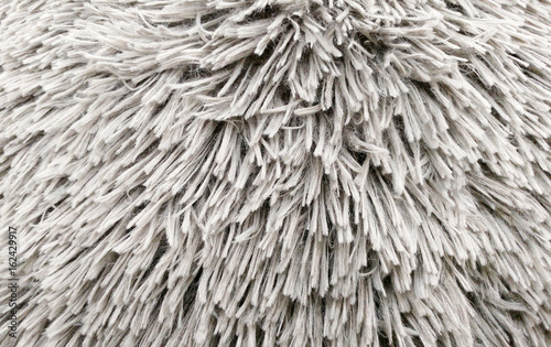Fluffy texture fabric. Closeup of the pillow with gray fur cover. Abstract background.