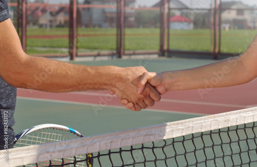 Young players shaking hands on tennis court, only hands can be seen. © Nastassia Yakushevic