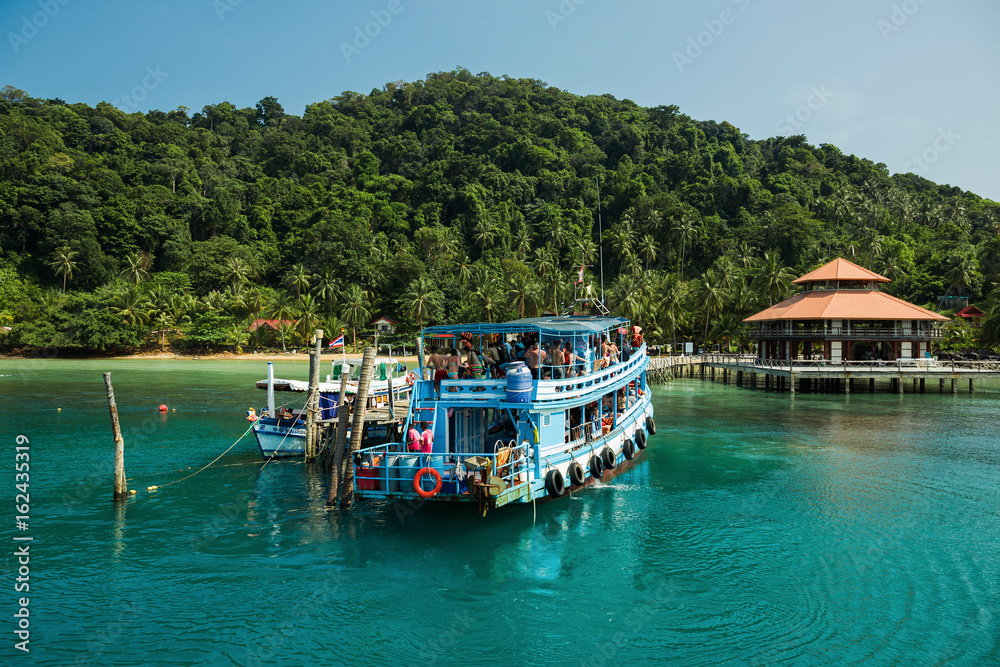 Ship with tourists on a tropical island beach