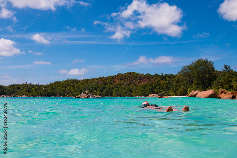 Woman floating in the ocean at Anse Lazio, Praslin, Seychelles