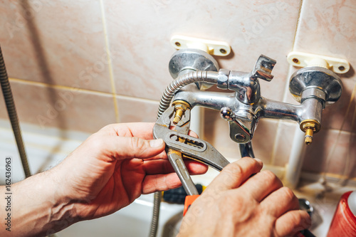 Man repair and fixing leaky old faucet in bathroom