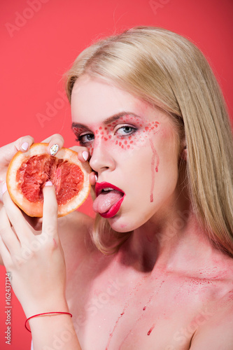grapefruit in hands of woman with creative fashionable makeup, vitamin