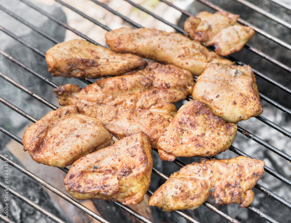 Grilling chicken breast on barbecue grill 