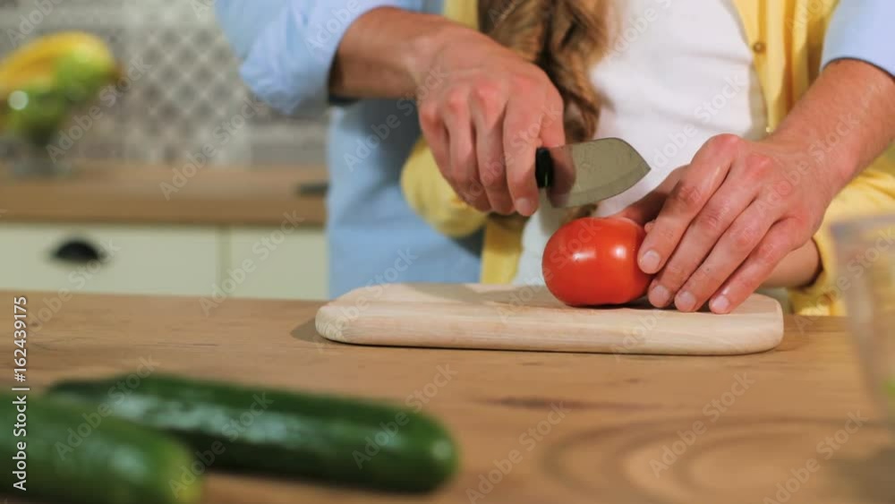 Close up shot of father hands cutting the tomato, daughter help cutting the ingredients. Close up shot of father hands cutting the tomato, daughter help cutting the ingredients.