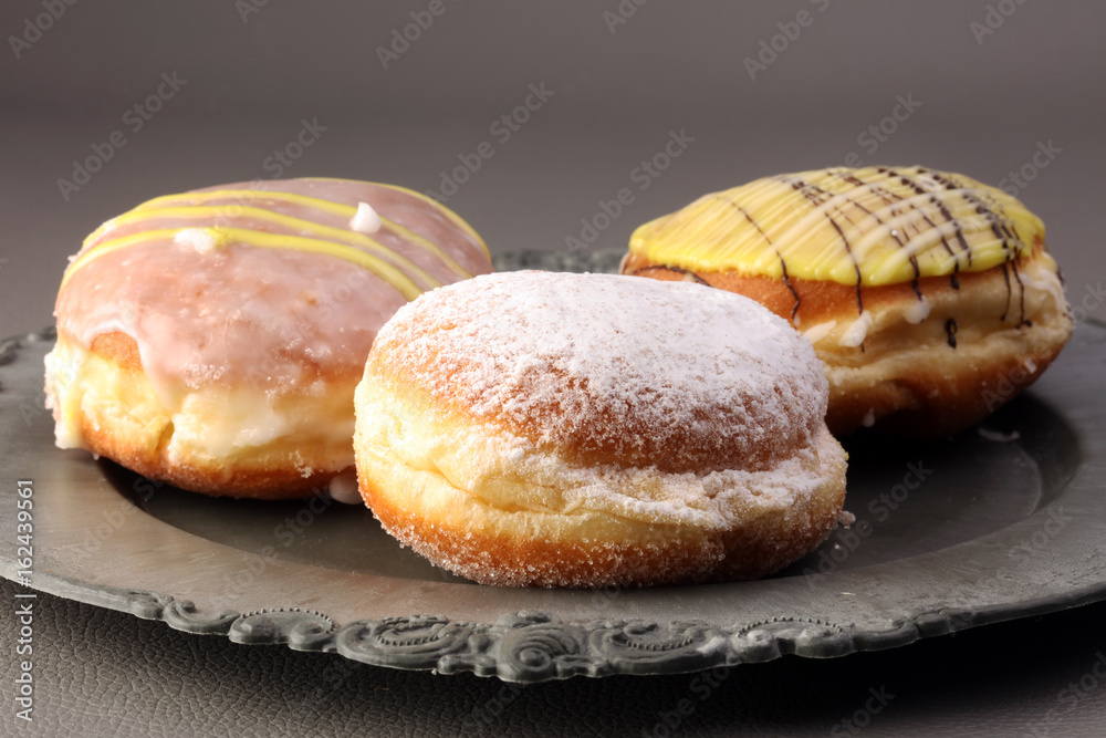 German donuts - berliner with jam and icing sugar in a tray on a grey background. German donuts - berliner with jam and icing sugar in a tray on a grey background.