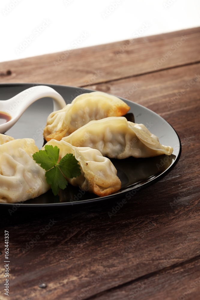 A plate of Japanese gyoza dumplings sitting on a rustic wooden t