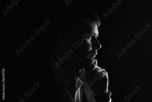 Man low key high-contrast profile portrait in backlight with a serious look on his face