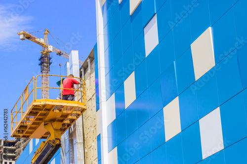A worker installs panels facing on the facade of the house