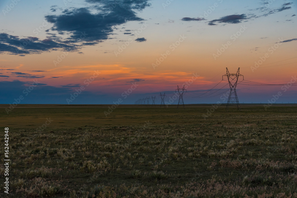 Obraz premium Electrical Transmission Towers at Sunset on the Plains