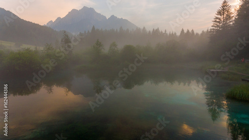Morning mists rising above forest lake.