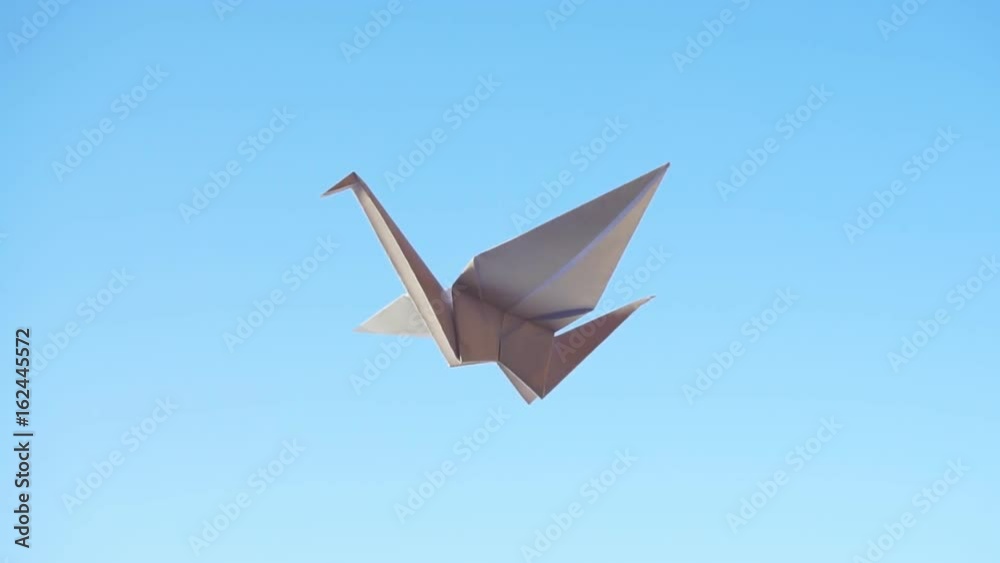 Origami Bird. Flying origami bird on blue background