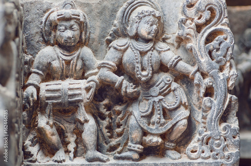 Musician with indian drum and lady dancing in traditional style. Stone relief of the 12th century Hindu temple Hoysaleshwara in Halebidu, India