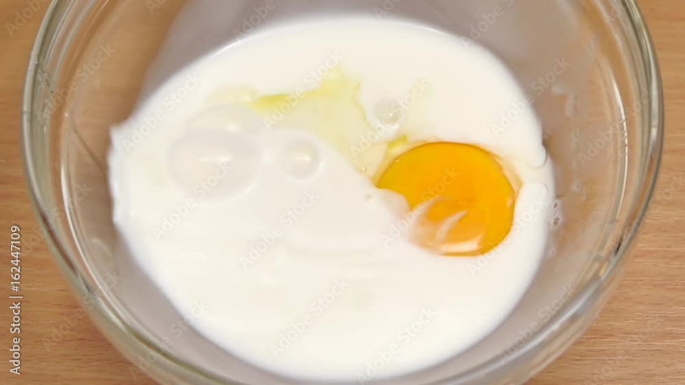 One fresh chicken egg is broken in plate with milk One fresh chicken egg is broken in plate with milk