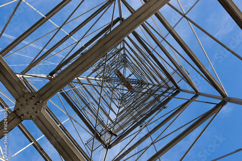 Looking upwards while standing underneath an electrical tower